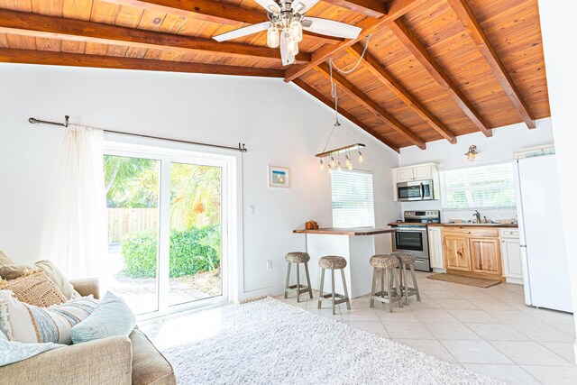 kitchen with appliances with stainless steel finishes, sink, a breakfast bar area, hanging light fixtures, and beam ceiling