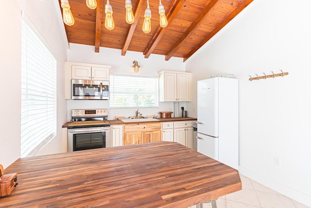 kitchen with wood counters, lofted ceiling with beams, sink, hanging light fixtures, and stainless steel appliances