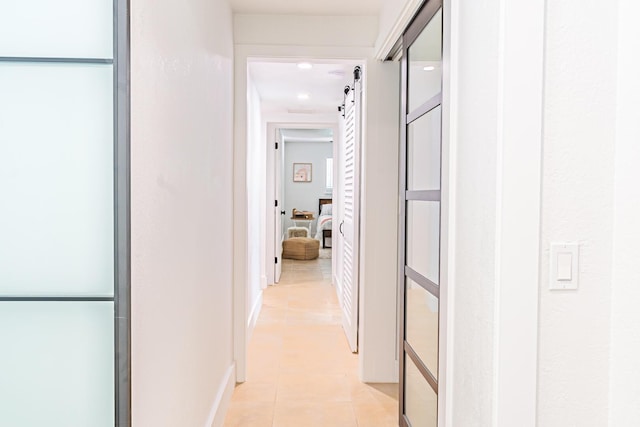 hall with a barn door and light tile patterned flooring