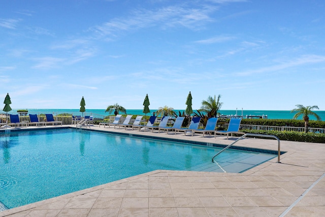 view of pool with a patio, a water view, and fence