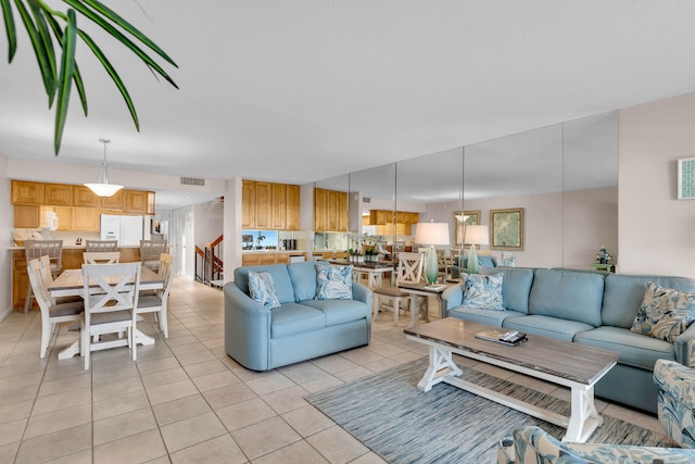 living room featuring stairway, visible vents, and light tile patterned flooring