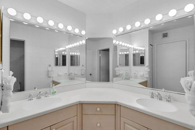 bathroom with double vanity, visible vents, and a sink