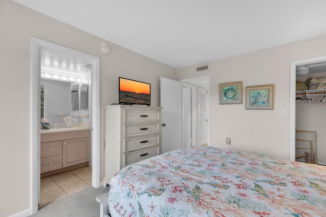 bedroom with light carpet, visible vents, ensuite bathroom, a spacious closet, and a closet