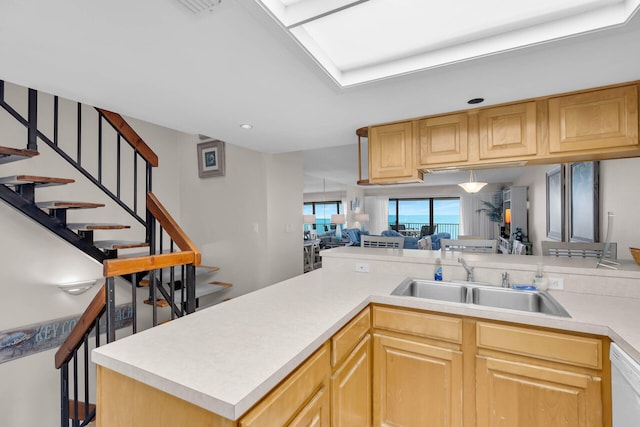 kitchen featuring white dishwasher, light countertops, a sink, and open floor plan