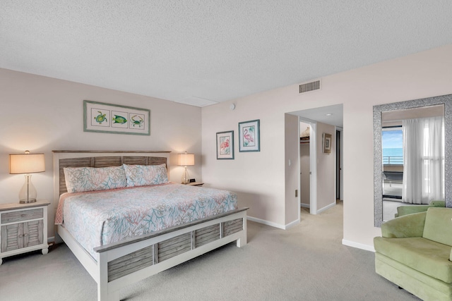 bedroom featuring baseboards, light colored carpet, visible vents, and a textured ceiling