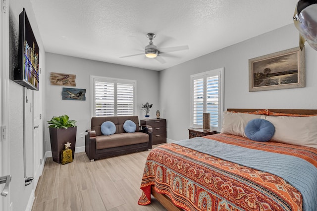 bedroom featuring multiple windows, ceiling fan, a textured ceiling, and light hardwood / wood-style floors