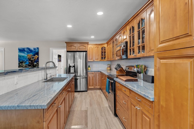 kitchen featuring stainless steel appliances, light stone countertops, and sink