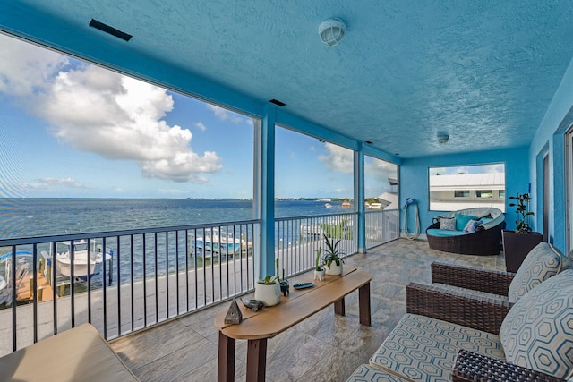 sunroom featuring a water view and a view of the beach