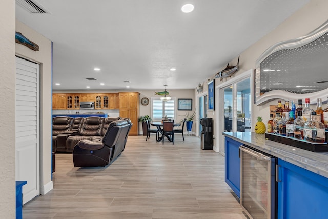 interior space featuring blue cabinetry, light stone counters, wine cooler, and light hardwood / wood-style floors