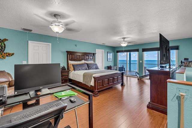 bedroom with access to exterior, hardwood / wood-style flooring, a textured ceiling, and ceiling fan