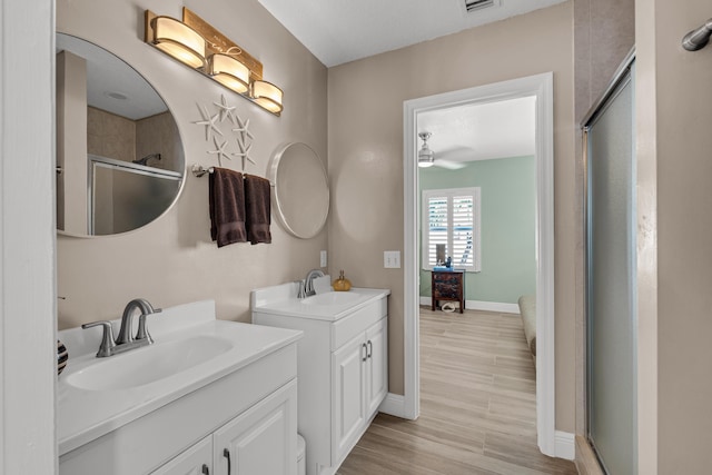 bathroom with hardwood / wood-style flooring, ceiling fan, vanity, and an enclosed shower