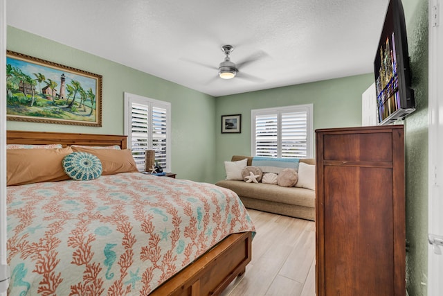 bedroom featuring ceiling fan, a textured ceiling, and light wood-type flooring