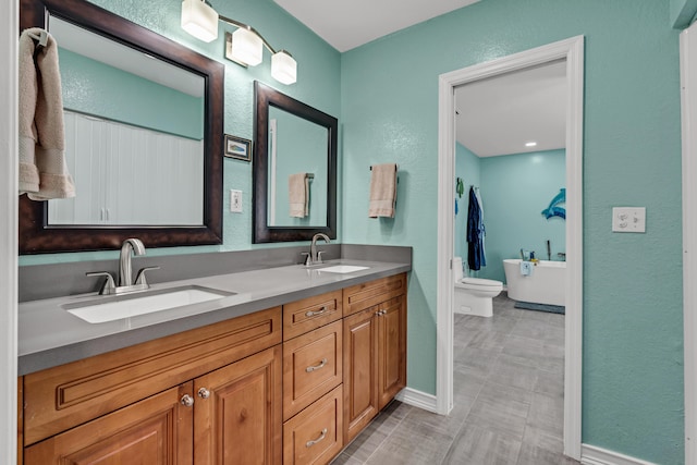 bathroom featuring vanity, a tub to relax in, and toilet