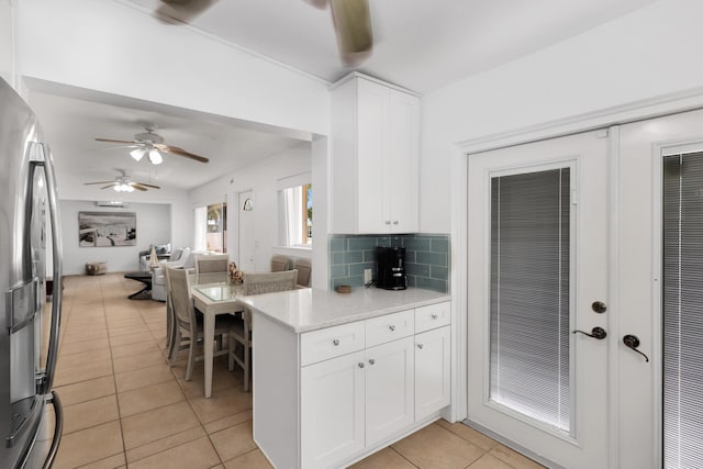 kitchen featuring white cabinets, backsplash, light tile patterned floors, light stone counters, and stainless steel fridge with ice dispenser