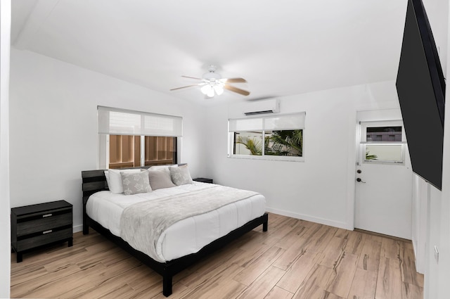 bedroom with ceiling fan, light hardwood / wood-style floors, and a wall unit AC