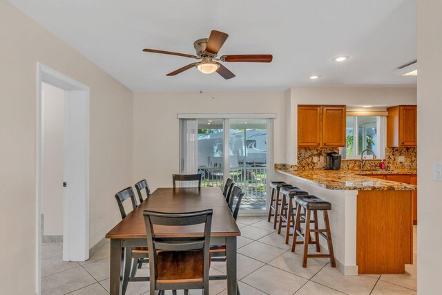 tiled dining area featuring ceiling fan, plenty of natural light, and sink