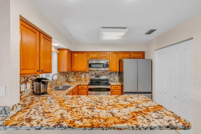 kitchen with appliances with stainless steel finishes, kitchen peninsula, sink, and decorative backsplash