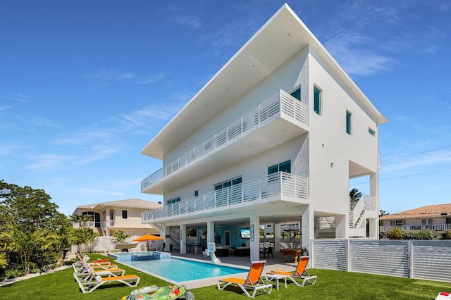 rear view of property with a fenced in pool, a balcony, a patio area, and a lawn