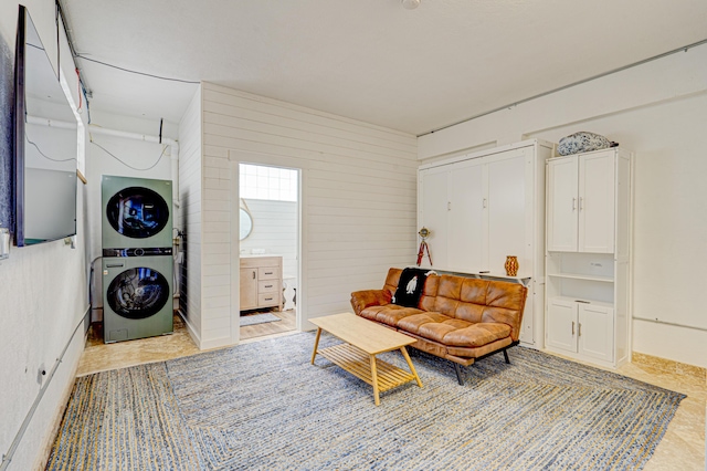 sitting room featuring wooden walls and stacked washing maching and dryer