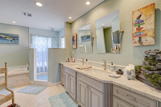 bathroom featuring a textured wall, visible vents, a sink, and a bath