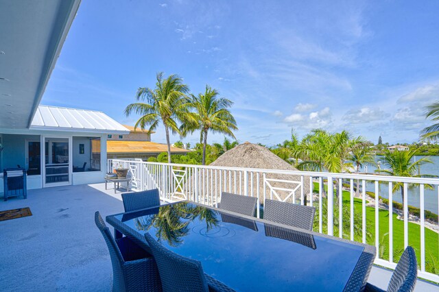 wooden deck featuring a yard, outdoor dining space, a water view, and a sunroom