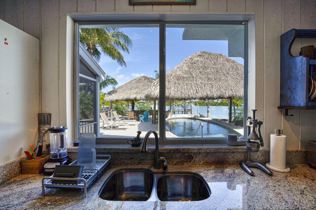 kitchen featuring stone counters, a water view, and a sink