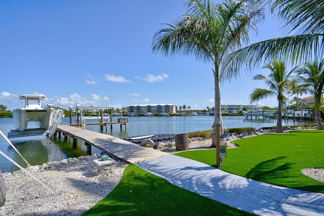 dock area with a water view, boat lift, and a yard