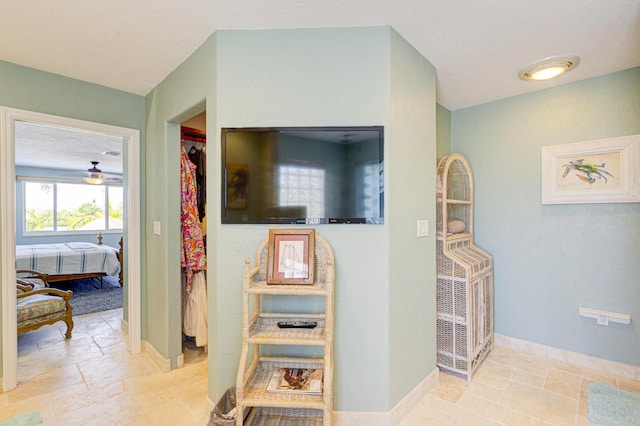 corridor featuring a textured ceiling, baseboards, and stone tile flooring