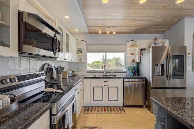 kitchen with dark stone counters, glass insert cabinets, stainless steel appliances, open shelves, and a sink