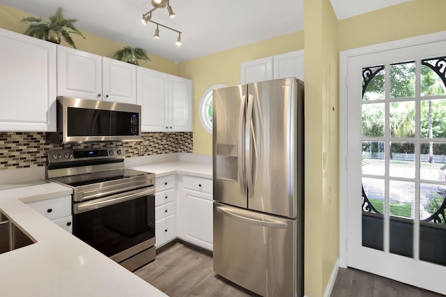 kitchen with appliances with stainless steel finishes, a wealth of natural light, white cabinets, and backsplash