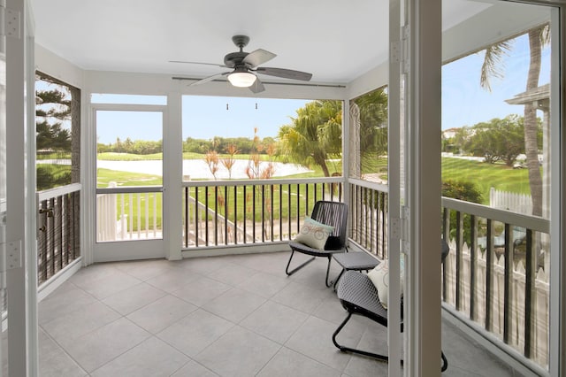 sunroom / solarium with a water view and ceiling fan