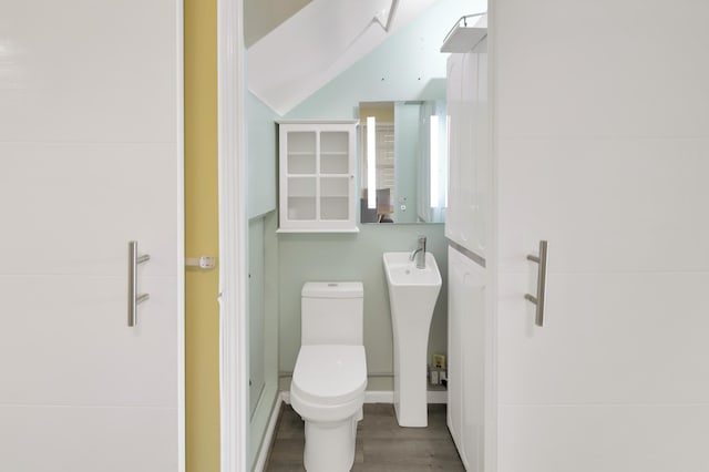 bathroom with vaulted ceiling, hardwood / wood-style floors, and toilet