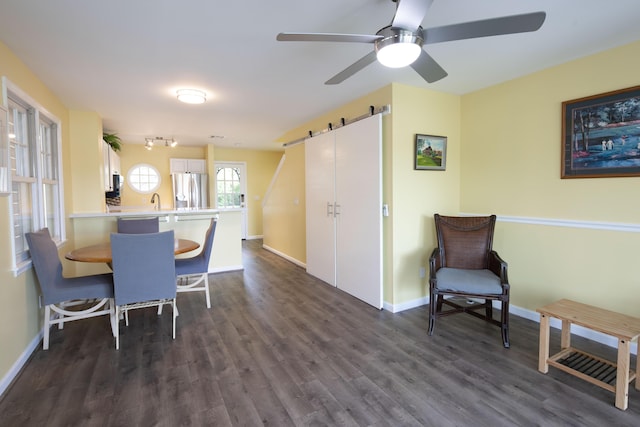 dining space with dark hardwood / wood-style floors, ceiling fan, a barn door, and sink