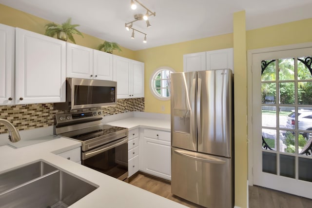 kitchen with white cabinetry, appliances with stainless steel finishes, sink, and backsplash