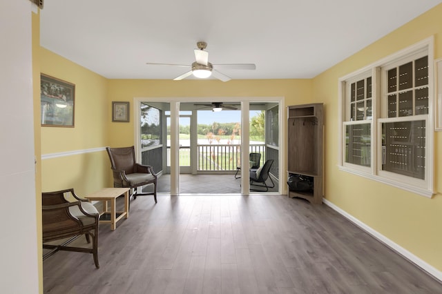 sitting room with ceiling fan and wood-type flooring