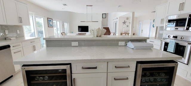 kitchen with wine cooler, decorative backsplash, appliances with stainless steel finishes, and a kitchen island