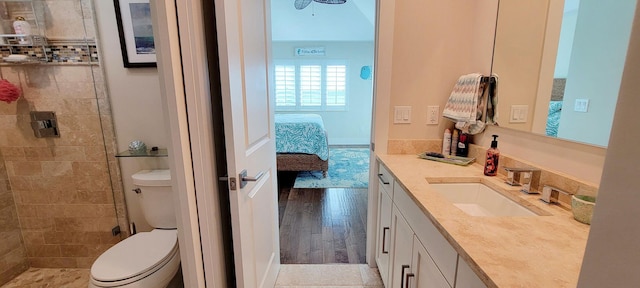 ensuite bathroom with ensuite bathroom, toilet, wood finished floors, tiled shower, and vanity