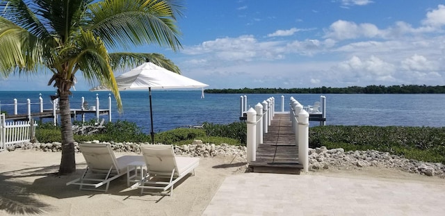 view of patio with a water view and a dock