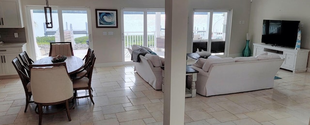 living area with baseboards, stone tile floors, and a healthy amount of sunlight