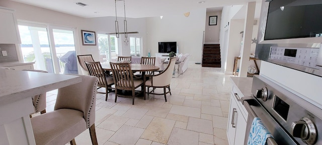 dining space with visible vents, stairway, and stone tile flooring