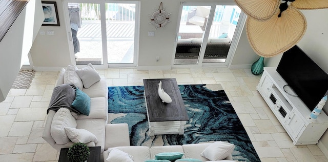 living area featuring baseboards and stone tile floors