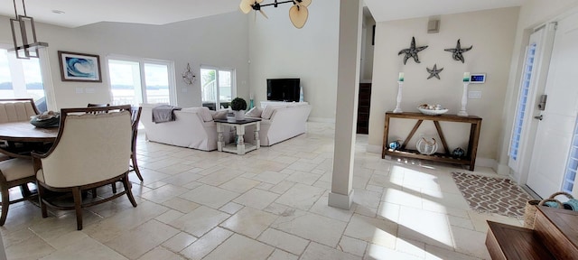 dining space with a high ceiling, stone tile floors, and baseboards