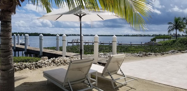 view of patio with a water view and a dock
