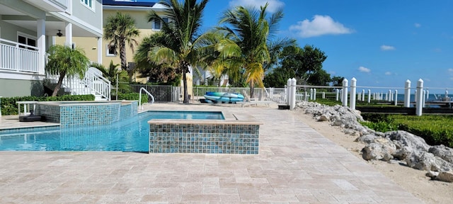 view of pool featuring a pool with connected hot tub, a patio, fence, and stairs