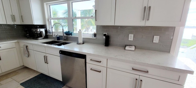 kitchen with white cabinetry, decorative backsplash, a sink, and stainless steel dishwasher