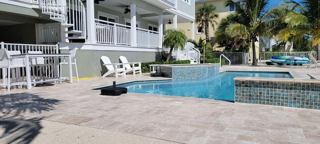 view of pool featuring fence, stairs, a patio, a ceiling fan, and a pool with connected hot tub