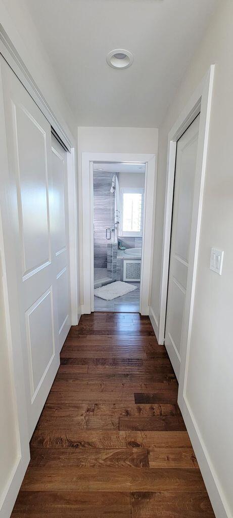 corridor featuring baseboards and dark wood-style flooring