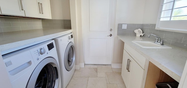 washroom featuring independent washer and dryer, a sink, cabinet space, and stone tile floors