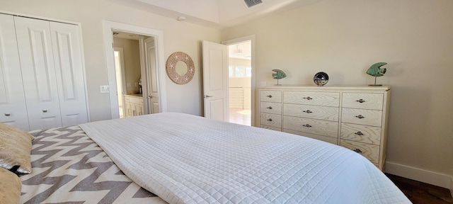 bedroom featuring baseboards, visible vents, a closet, and wood finished floors