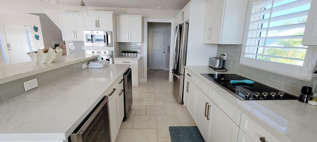 kitchen featuring appliances with stainless steel finishes, white cabinetry, stone tile floors, and beverage cooler